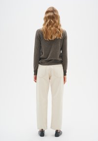 Grå långärmad tröja, off-white vida byxor och svarta skor. Sedd bakifrån, vilket framhäver tyg och passform.