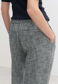 Grijze houndstooth broek met een hoge tailleband, zijzakken en een relaxed fit. Heeft een subtiele textuur en een gladde stoffen afwerking.