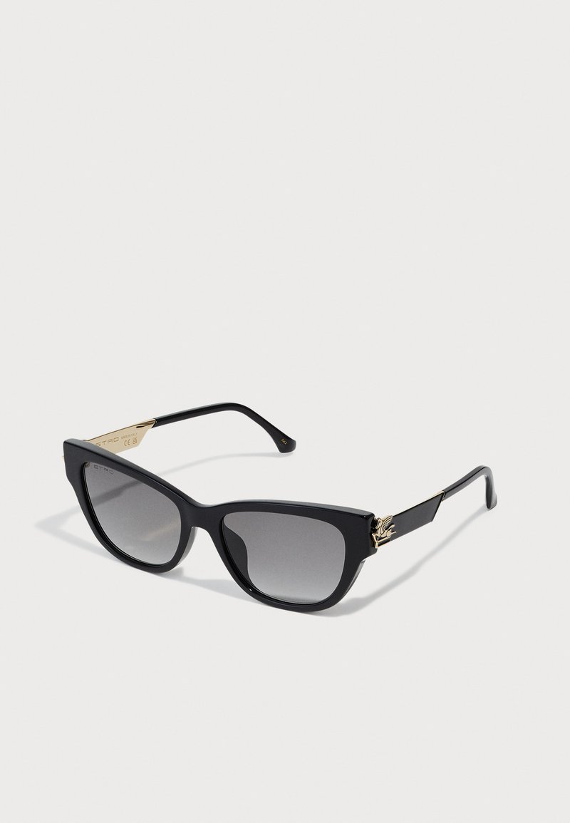Schwarze Cat-Eye-Sonnenbrille mit grauen Farbverlauf-Gläsern. Verfügt über goldene Akzente an den Bügeln. Glatter Kunststoffrahmen mit glanzvoller Oberfläche.