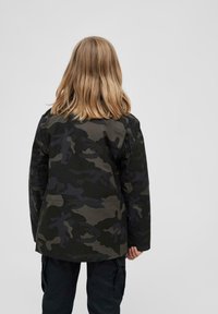 Tarnjacke in dunkelgrün und schwarzen Tönen, mit entspannter Passform, langen Ärmeln und geradem Saum. Rückansicht mit einfachem Design.
