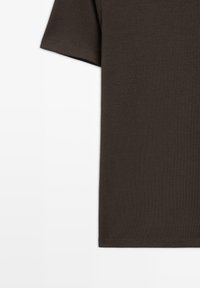 Donkerbruine, kortekorte t-shirt gemaakt van zachte katoenstof. Heeft een ronde halslijn en schone, minimalistische stiksels langs de randen.