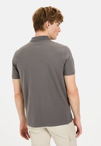 Grijze polo met een effen ontwerp, korte mouwen en een kraag. De achterkant heeft een gladde textuur en een relaxte fit.