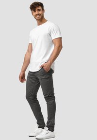 Camiseta blanca de algodón, jeans gris ajustados y zapatillas blancas. El conjunto presenta un estilo casual y moderno con líneas simples y un detalle minimalista.