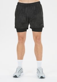 Svarta träningsshorts med ett subtilt mönster, utrustade med resårmidja och inbyggd kompressionsskikt. Matchas med grå löparskor.