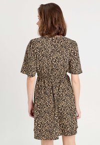 Robe à manches courtes imprimée léopard en beige et noir, avec une taille élastique et une coupe décontractée. Tissu lisse avec un léger éclat.
