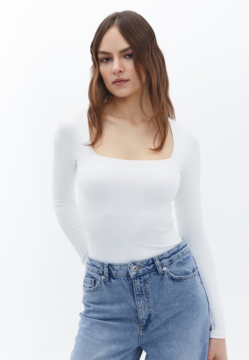 Witte long-sleeve bodysuit met een vierkante halslijn, een gladde textuur, gecombineerd met hooggetailleerde lichtblauwe denim jeans met een klassieke vijfvakdesign.