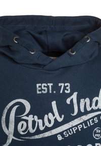 Felpa blu navy con cappuccio, stringa, occhielli in metallo e finitura testurizzata. Presenta testo bianco in stile vintage che dice "Petrol Ind. EST. 73."