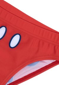 Rote Schwimmshorts mit glatter Oberfläche. Mit weißen ovalen Mustern und einer kontrastierenden Innenauskleidung in Hellblau mit Punkten.