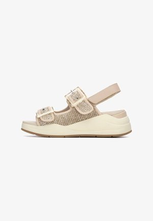 Sandalias beige con parte superior tejida y texturizada, dobles correas ajustables y una suela gruesa de color crema, con un diseño de ligera cresta para soporte.