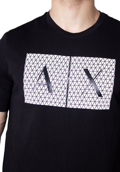 T-shirt en coton noir avec un imprimé géométrique blanc représentant les lettres "A" et "X" en noir gras, col rond, manches courtes.
