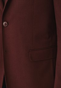 Burgundowa marynarka z teksturowanej tkaniny, zapinana na jeden guzik, z eleganckim wzorem kieszeni. Dopasowany krój z subtelnymi detalami przeszyć.