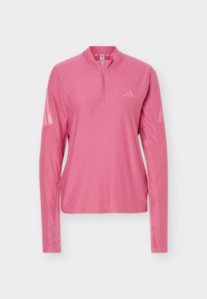 Haut de course rose pour femmes à manches longues avec col à zip quart, logo discret sur la poitrine et détails rayés sur le haut des manches.