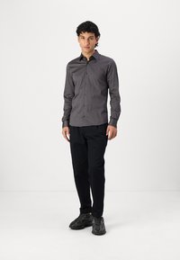Gray patterned button-up shirt with a slim fit, long sleeves, and a collar, paired with dark pants and black textured sneakers.