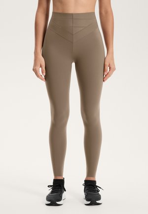 Leggings de antrenament bej cu talie înaltă, cu o textură netedă, prezentând linii de design triunghiulare la talie și o siluetă ajustată.