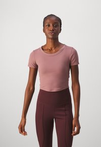 Lühikeste käistega, lühike särk pehmest mauve kangast ümara kaelusega, kombineeritud kõrge vöökoha tumedate burgundia sõlmüksustega, millel on õmblustead.