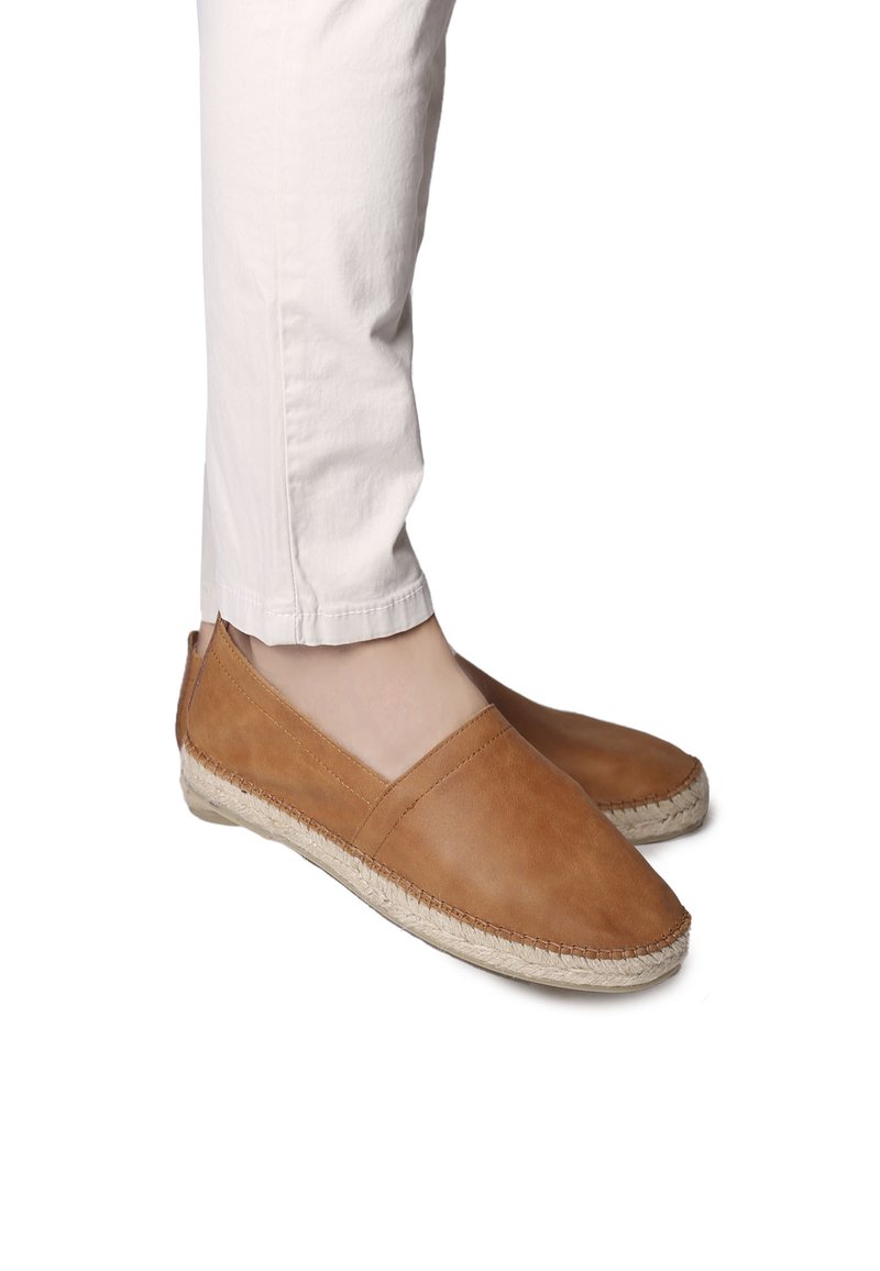 Ljusbruna läderskor med slip-on-design och en platt espadrillesula, med rund tå och diskret sömnad längs kanterna.