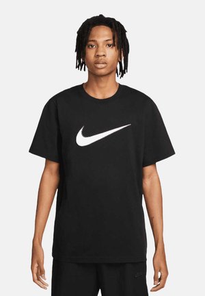T-shirt in cotone nero con un prominente logo swoosh bianco di Nike sul petto, maniche corte e design a girocollo.