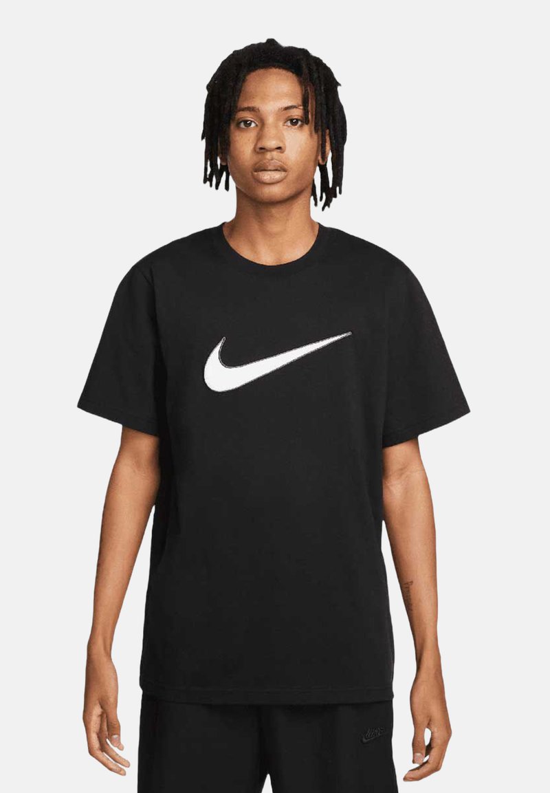 T-shirt in cotone nero con un prominente logo swoosh bianco di Nike sul petto, maniche corte e design a girocollo.