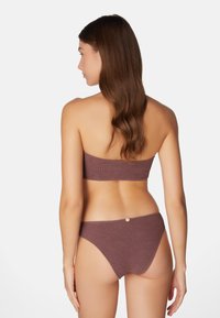 Brun stickad bikini med en bandeau-topp och lågt skurna underdelar med en knappdetalj, som visar en texturerad tyg och sömlös design.