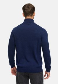 Navyblauer gestrickter Pullover mit hohem Kragen sowie gerippten Bündchen und Saum, der einen strukturierten, weichen Stoff zeigt. Rückansicht mit taillierter Silhouette.