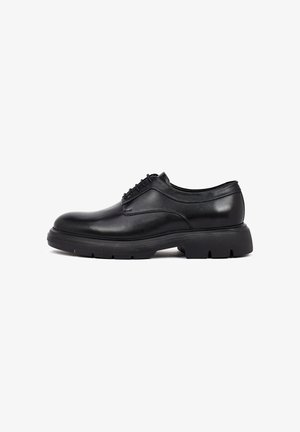Chaussure en cuir noir avec un bout rond, lacets à l'avant et semelle en caoutchouc texturé. Présente une finition lisse et un design minimaliste.