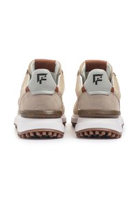 Baskets en daim beige et mesh avec des accents en cuir brun, semelle intermédiaire blanche, dotées d'une semelle extérieure texturée et d'un logo au niveau du talon.