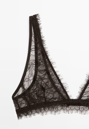 Bralette in pizzo nero con coppe triangolari, tessuto in pizzo floreale trasparente e delicata rifinitura con frange lungo i bordi su sfondo bianco.