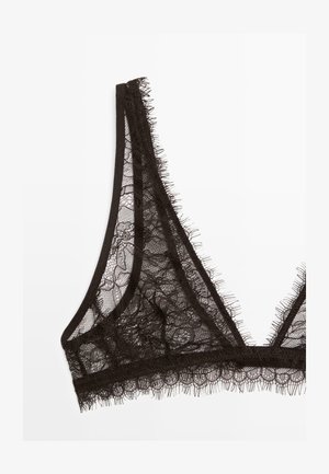 Bralette in pizzo nero con coppe triangolari, tessuto in pizzo floreale trasparente e delicata rifinitura con frange lungo i bordi su sfondo bianco.