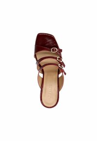 Red patent leather heel with a square toe, featuring three thin straps with circular buckles. Smooth inner lining with embossed brand name.
