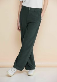 Mörkgröna vida byxor i slät tyg, med knappstängning, elastisk midja och sidofickor.