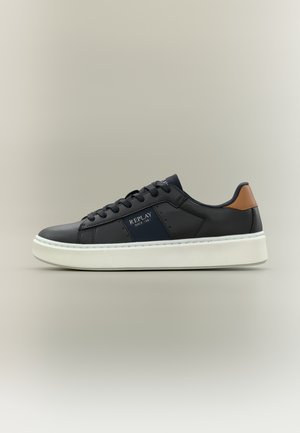 Sneaker nero basso con suola bianca, dettaglio marrone sul tallone e logo "REPLAY Since 1981" sul pannello laterale blu navy, mostrato su sfondo neutro.