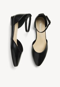 Chaussures plates en cuir noir avec un bout pointu, des côtés ouverts et une bride au niveau de la cheville. L'intérieur est doublé de beige. Taille marquée 37.