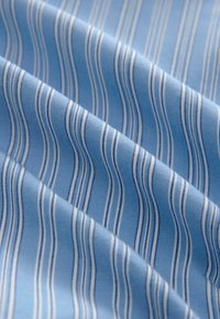 Light blue fabric with white and light gray wavy stripes, made of smooth material with a soft texture, showcasing a flowing pattern.