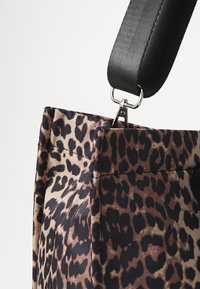 Tote-väska med leopardmönster, svart justerbar rem, rektangulär form, texturerad tyg och metallisk hårdvarufäste.