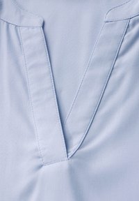 Blusa azzurro chiaro con scollatura a V, pieghe sottili alle spalle e una texture morbida con dettagli di cucitura ordinati.