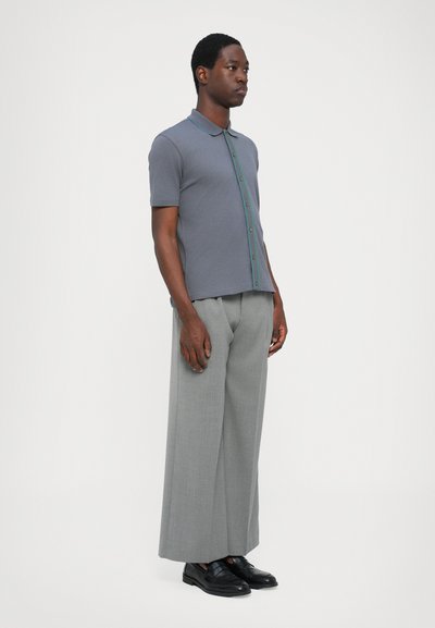 Gray polo shirt with a contrasting teal button placket, paired with light gray wide-leg trousers and black shoes. Simple and modern design.