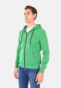 Felpa verde con zip realizzata in misto cotone, con tasca frontale, cappuccio regolabile con coulisse e polsini e orlo a coste.