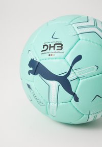 Lyseblå håndbold med et marineblå Puma-logo, teksturerede paneler og trykte geometriske mønstre. Viser branding for Deutscher Handballbund.