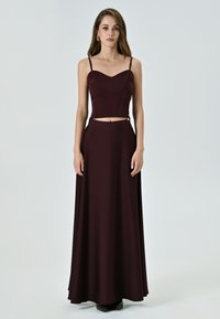 Abito bordeaux a due pezzi con top corto aderente dotato di spalline regolabili e una gonna fluida a forma A, realizzato in un tessuto liscio.