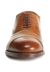 Bruine leren pumpschoenen met een ronde neus, met een gladde textuur en zes eylets voor veters, geplaatst op een donkere houten zool.