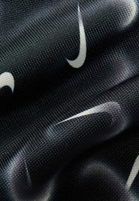 Tissu noir avec une surface texturée arborant un logo Nike en forme de swoosh blanc répétitif. L'ensemble du design est dynamique et moderne.