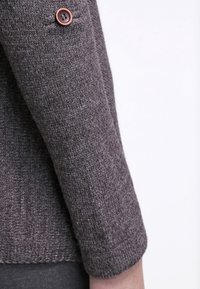 Maglione leggero grigio scuro a maglia con una finitura testurizzata e un polsino rotondo, caratterizzato da un bottone marrone decorativo sulla manica.