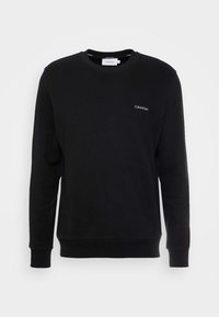 Felpa nera in cotone con maniche lunghe, scollatura a girocollo e polsini a costine. Presenta un piccolo logo bianco di Calvin Klein sul petto.