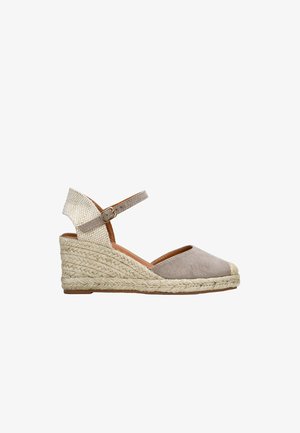 Espadrille cuña en ante beige claro, con tira de tobillo de tejido trenzado, suela envuelta en cuerda, punta redonda y base plana marrón.