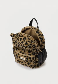 Mały pluszowy plecak w leopardzie, z przednią kieszenią na zamek, czarnymi bocznymi kieszeniami i uchwytem na górze na białym tle.
