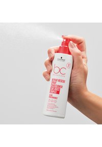 Bouteille pulvérisatrice blanche avec accents rouges ; l'étiquette inclut « bc Bonacure » et « Repair Rescue Spray Conditioner », buse diffusant le produit.