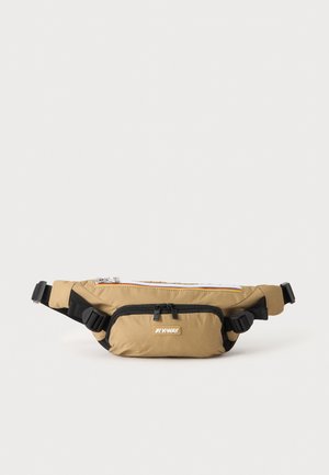 Sac banane beige avec des sangles noires réglables, deux compartiments zippés et un petit patch logo sur la poche avant.
