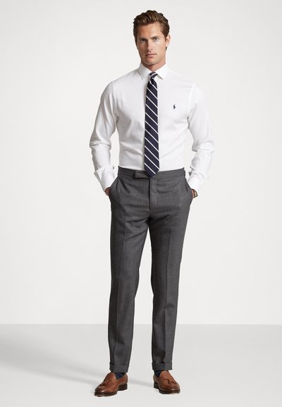 White long-sleeve shirt, navy striped tie, gray trousers, brown loafers. Simple design with a classic fit, showcasing neat tailoring details.
