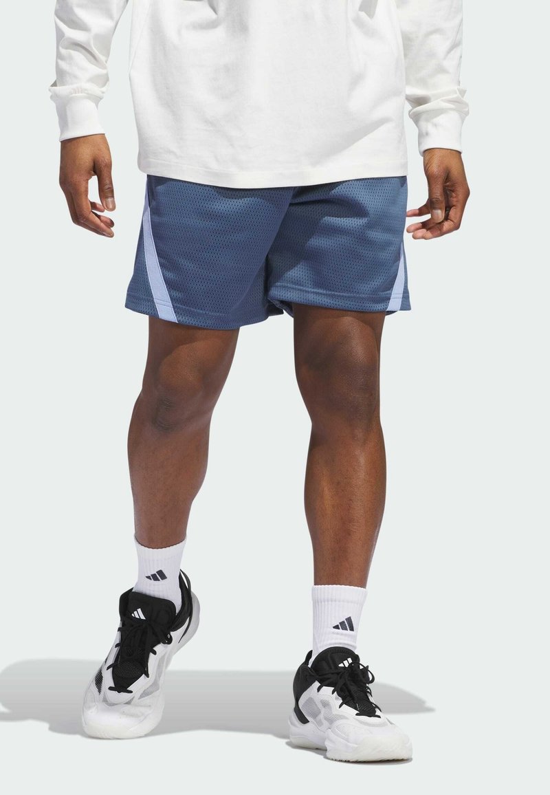 Shorts de sport en maille marine avec des bandes latérales bleu clair, assortis à des baskets noires et blanches, et des chaussettes blanches avec un logo.