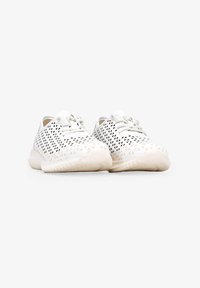 Zapatillas deportivas blancas con un diseño perforado, una plantilla con textura y cordones planos, que cuentan con una punta redondeada y un estilo minimalista.